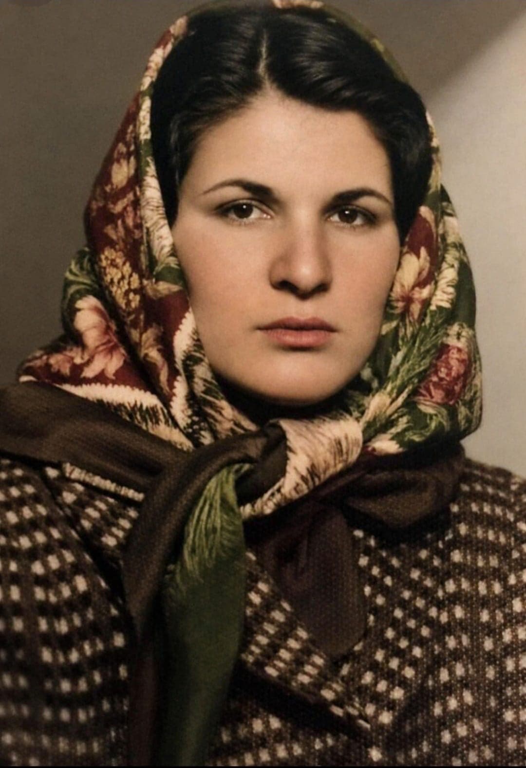 A vintage colour portrait of a young woman in a floral headscarf and a dotted wool coat.